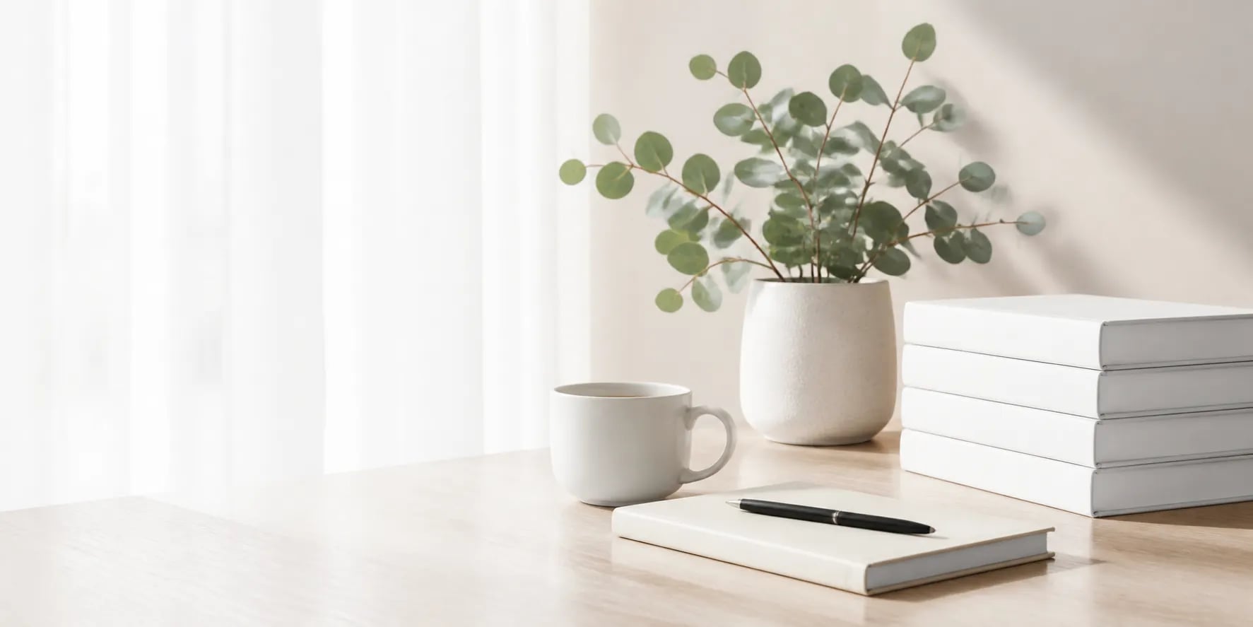 A bright workspace with technology books, a notebook, coffee and a plant