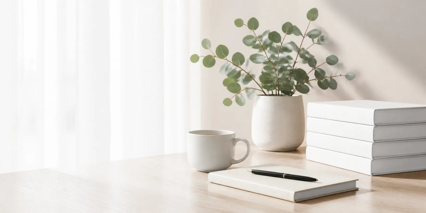 A bright workspace with technology books, a notebook, coffee and a plant